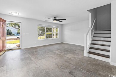 Unfurnished living room with a ceiling fan and stairs
