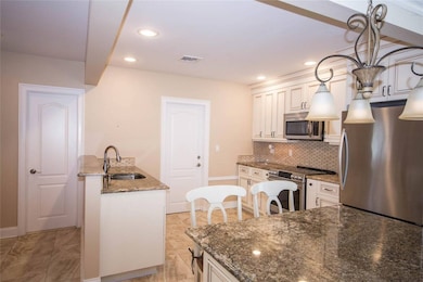 Kitchen with appliances with stainless steel finishes, decorative backsplash, recessed lighting, dark stone counters, and pendant lighting