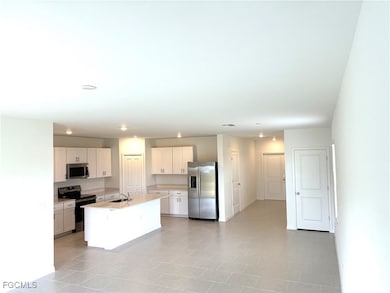Kitchen featuring stainless steel appliances, white cabinets, an island with sink, and light tile patterned flooring