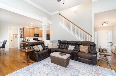 Well lit Living area featuring bamboo hardwoods, stairs, ornamental molding, ceiling fan, and baseboards.