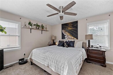 Bedroom with light colored carpet, a textured ceiling, and a ceiling fan