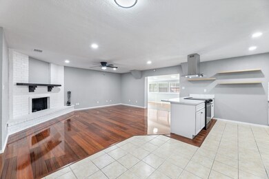 Kitchen with open shelves, light tile patterned floors, a ceiling fan, open floor plan, and a fireplace
