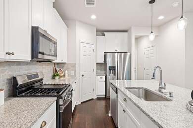 Kitchen with visible vents, white cabinets, a sin