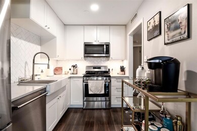 Kitchen with white cabinets, appliances with stai