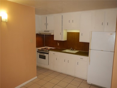 Kitchen with white appliances, a sink, dark counte