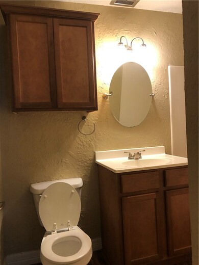 Half bath featuring vanity, toilet, a textured wal