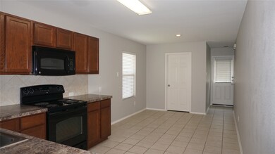 Kitchen with black appliances, dark countertops, healthy amount of natural light, light tile patterned floors, and recessed lighting