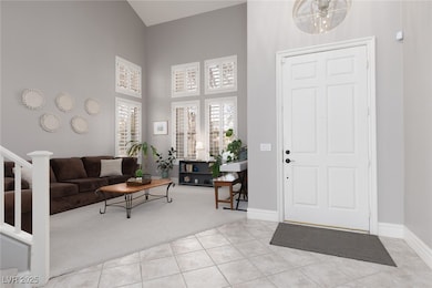 Tiled entryway featuring baseboards, a high ceilin