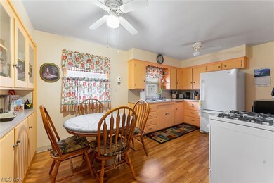 Kitchen featuring white appliances, sink, ceiling fan, and light wood-type flooring