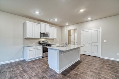 Kitchen featuring appliances with stainless steel finishes, light stone countertops, white cabinets, dark wood finished floors, and recessed lighting