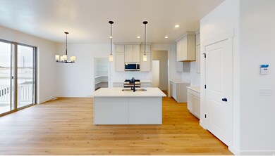 Kitchen with recessed lighting, an island with sink, appliances with stainless steel finishes, light wood finished floors, and white cabinetry