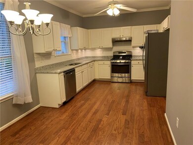 Kitchen with stainless steel appliances, a chandelier, ceiling fan, white cabinets, and ornamental molding