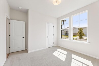Unfurnished bedroom with light colored carpet and baseboards
