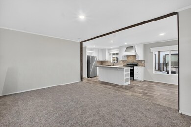 Kitchen with ornamental molding, open floor plan, white cabinetry, healthy amount of natural light, and appliances with stainless steel finishes