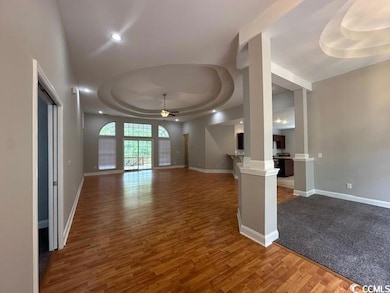 Unfurnished living room featuring a tray ceiling, a ceiling fan, light wood-style floors, and recessed lighting