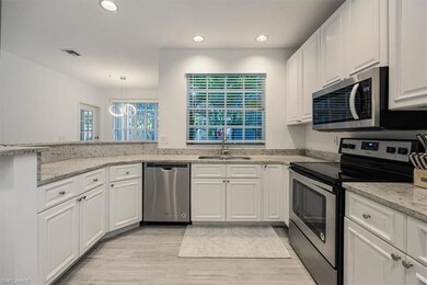 Kitchen featuring stainless steel appliances, white cabinetry, recessed lighting, light wood-style floors, and light stone countertops