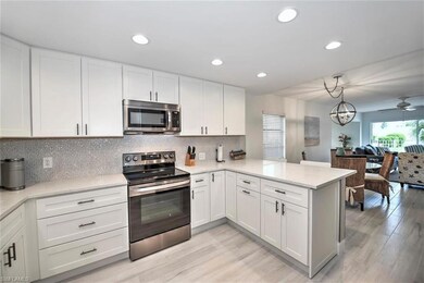 Kitchen with stainless steel appliances, a peninsula, light countertops, light wood-style flooring, and white cabinetry