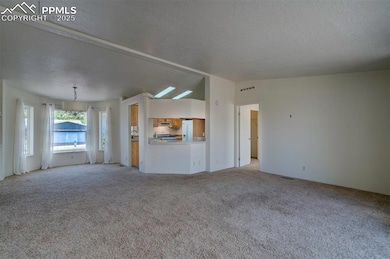 Unfurnished living room featuring a textured ceiling and light colored carpet