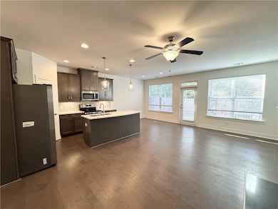 Kitchen featuring appliances with stainless steel finishes, pendant lighting, recessed lighting, open floor plan, and dark brown cabinetry