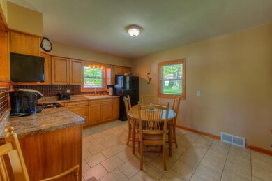 REMODELED EAT IN KITCHEN WITH MAPLE CABINETS AND GLASS BACK SPLASH AND APPLIANCES STAY