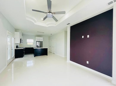 Unfurnished living room featuring a raised ceiling, light tile patterned floors, and ceiling fan