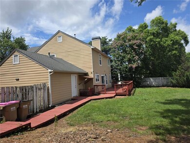 Back of house with a deck, a chimney, and a shingled roof