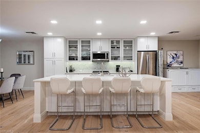 Kitchen with tasteful backsplash, a breakfast bar area, a spacious island, stainless steel appliances, and glass insert cabinets