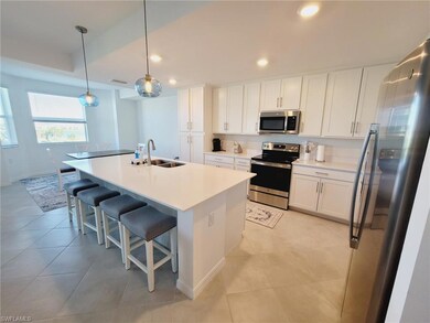 Kitchen with white cabinets, pendant lighting, stainless steel appliances, and a center island with sink