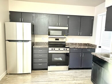 Kitchen featuring NEW appliances with stainless steel finishes, light wood finished floors, and dark cabinetry