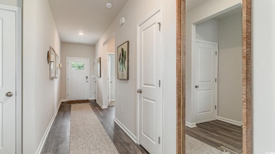 Hallway with dark wood-style flooring, baseboards, and recessed lighting