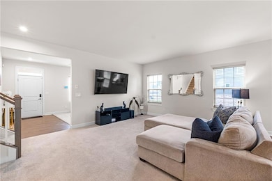 Carpeted living area with baseboards, stairs, and recessed lighting