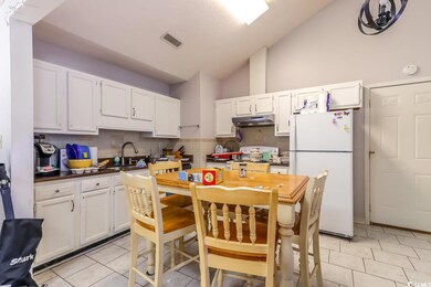 Kitchen featuring freestanding refrigerator, under cabinet range hood, stove, a sink, and white cabinetry