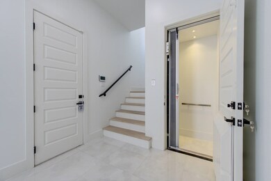 A modern entryway featuring a staircase, sleek tiled flooring, and a built-in residential elevator for convenience.