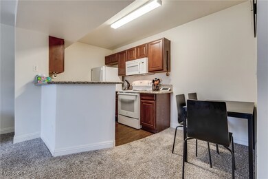 Kitchen featuring dark colored carpet, white appli