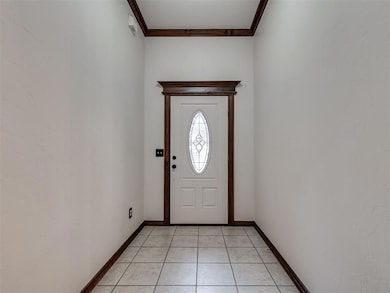Foyer featuring light tile patterned floors and ornamental molding
