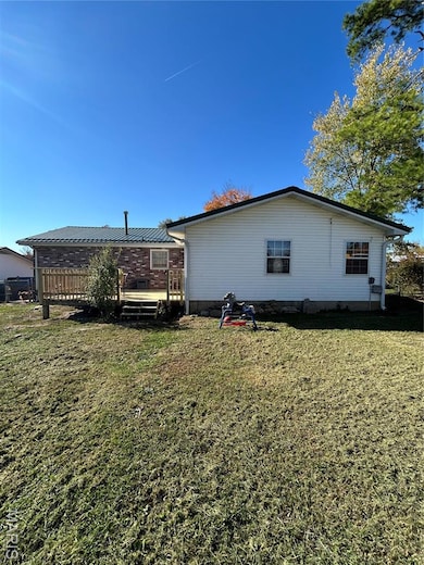 Rear view of property featuring a yard and a wooden deck