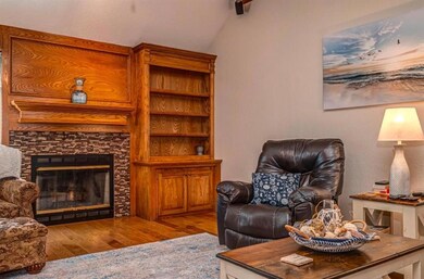 Living room featuring vaulted ceiling, wood finished floors, and a fireplace