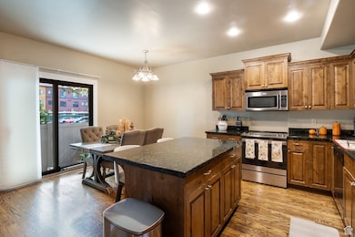 Kitchen with a center island, stainless steel appliances, light wood-type flooring, hanging light fixtures, and a chandelier