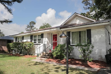 Ranch-style house with brick siding, a front yard, and metal roof