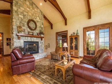 Living area featuring wood finished floors, beam ceiling, a fireplace, and high vaulted ceiling