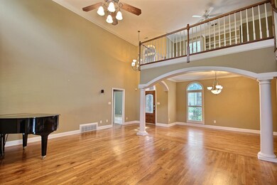 Great room featuring ceiling fan with notable chandelier, light hardwood / wood-style floors, and crown molding