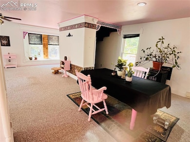 Carpeted dining room with a ceiling fan and baseboards