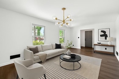 Living area featuring a chandelier, dark wood-style floors, and baseboards