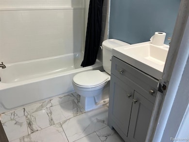 Bathroom featuring vanity, shower / bathtub combination with curtain, and light marble finish floors