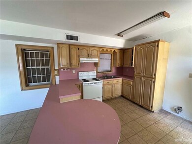 Kitchen featuring white electric range oven, under cabinet range hood, and a sink