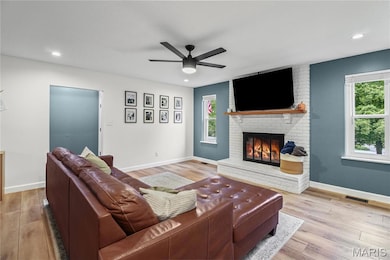 Living area with ceiling fan, light wood finished floors, a fireplace, and recessed lighting