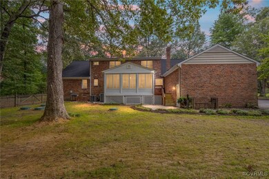 Back house at dusk featuring a lawn and a sunroom