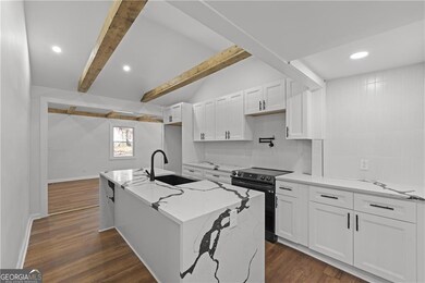 Kitchen with black electric range, a sink, white cabinetry, recessed lighting, and backsplash