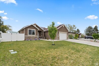 Single story home with stucco siding, stone siding, concrete driveway, and a gate
