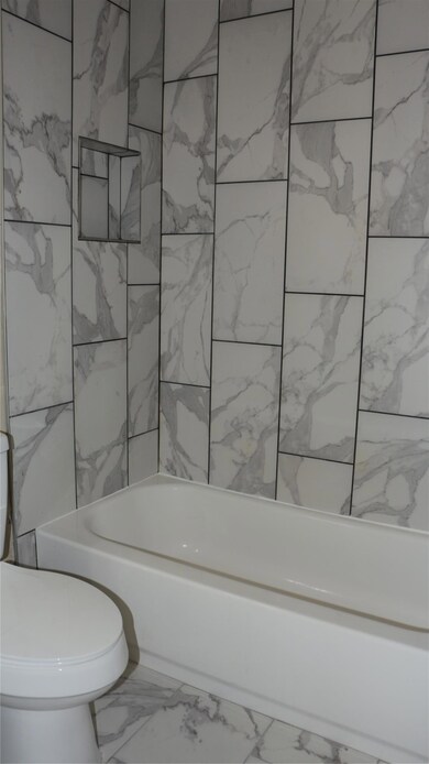 Bathroom featuring marble look tiles and shower /